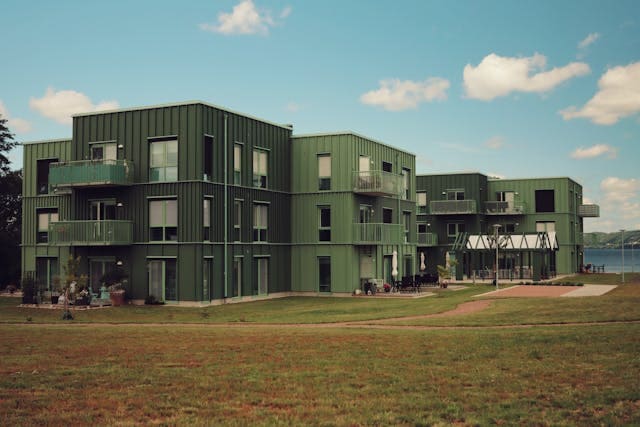 Cohousing verde con zonas comunes, césped y personas conviviendo en el exterior.