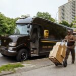 Repartidor de UPS entregando paquetes junto a un camión de reparto.