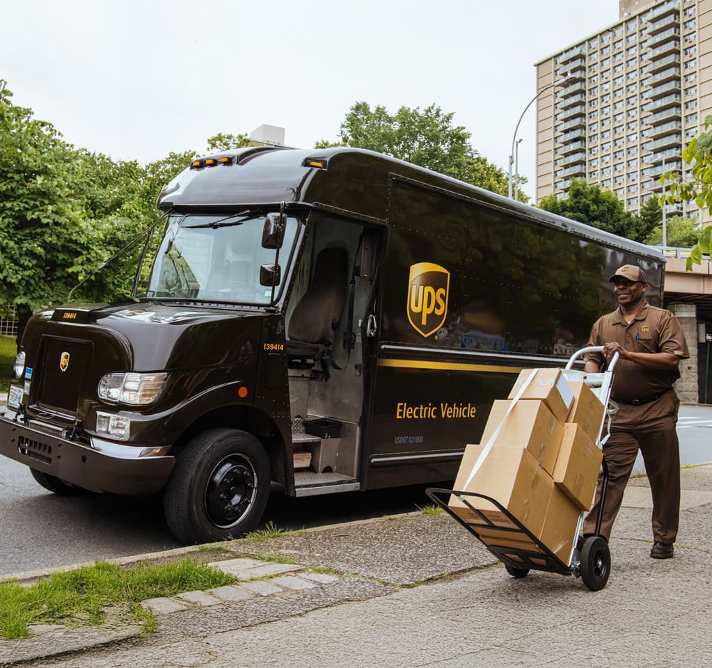 Repartidor de UPS entregando paquetes junto a un camión de reparto.